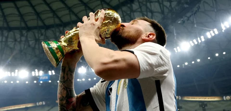 Игрок целует кубок мира на стадионе