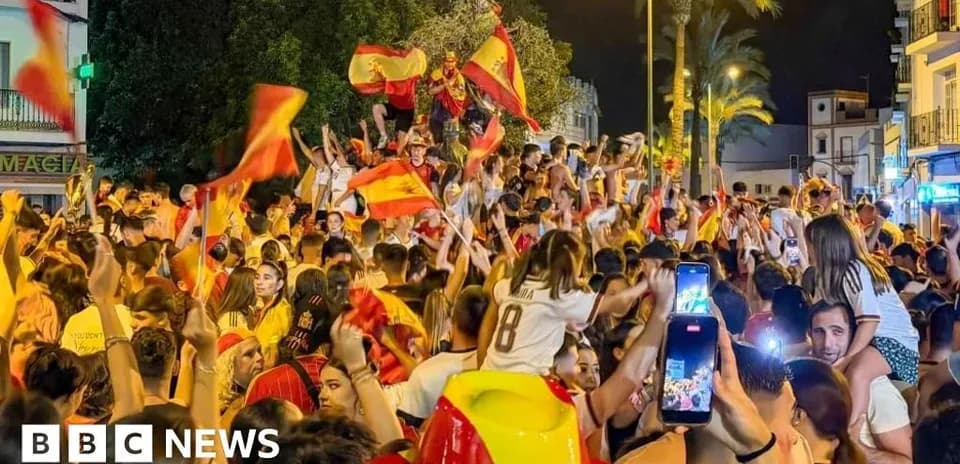 Толпа людей празднует с флагами Испании ночью