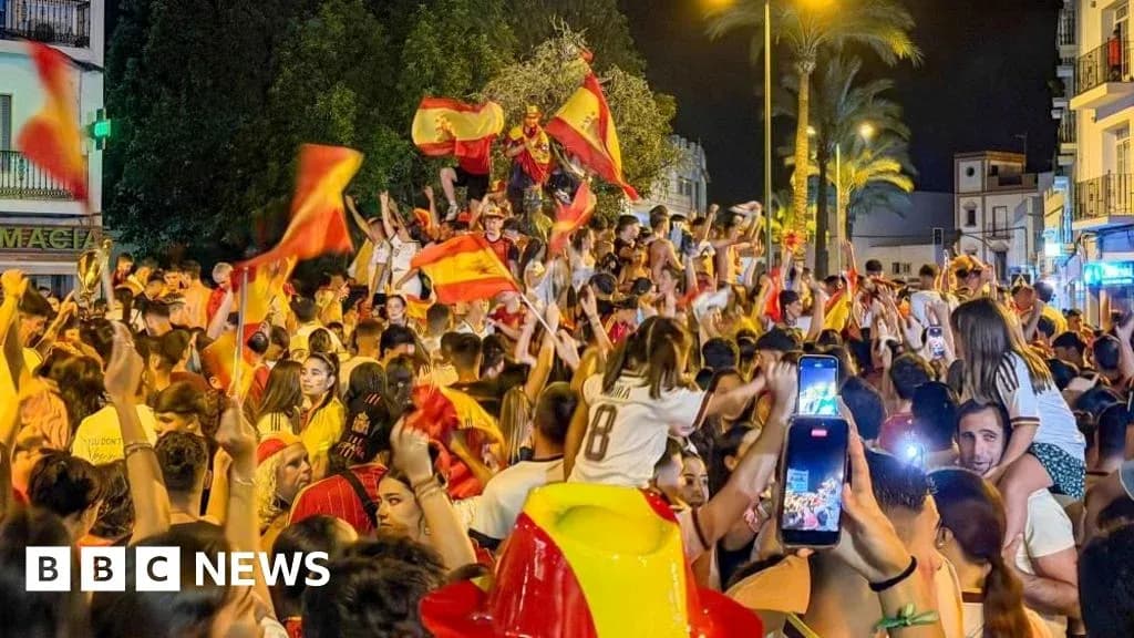 Толпа людей празднует с флагами Испании ночью