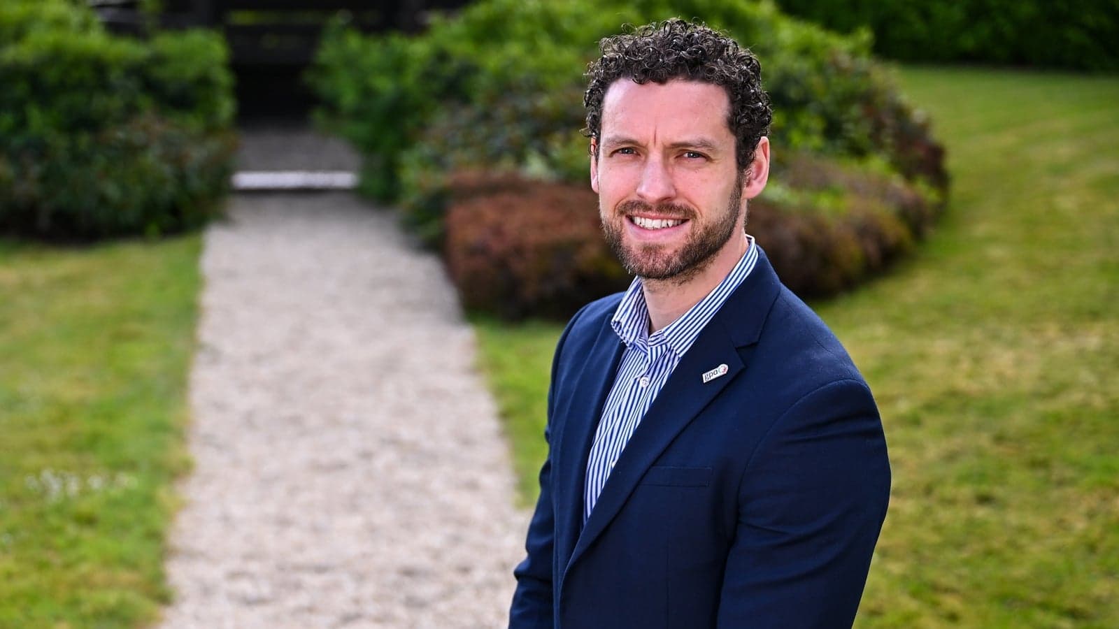 Человек в костюме на фоне зелени и дорожки