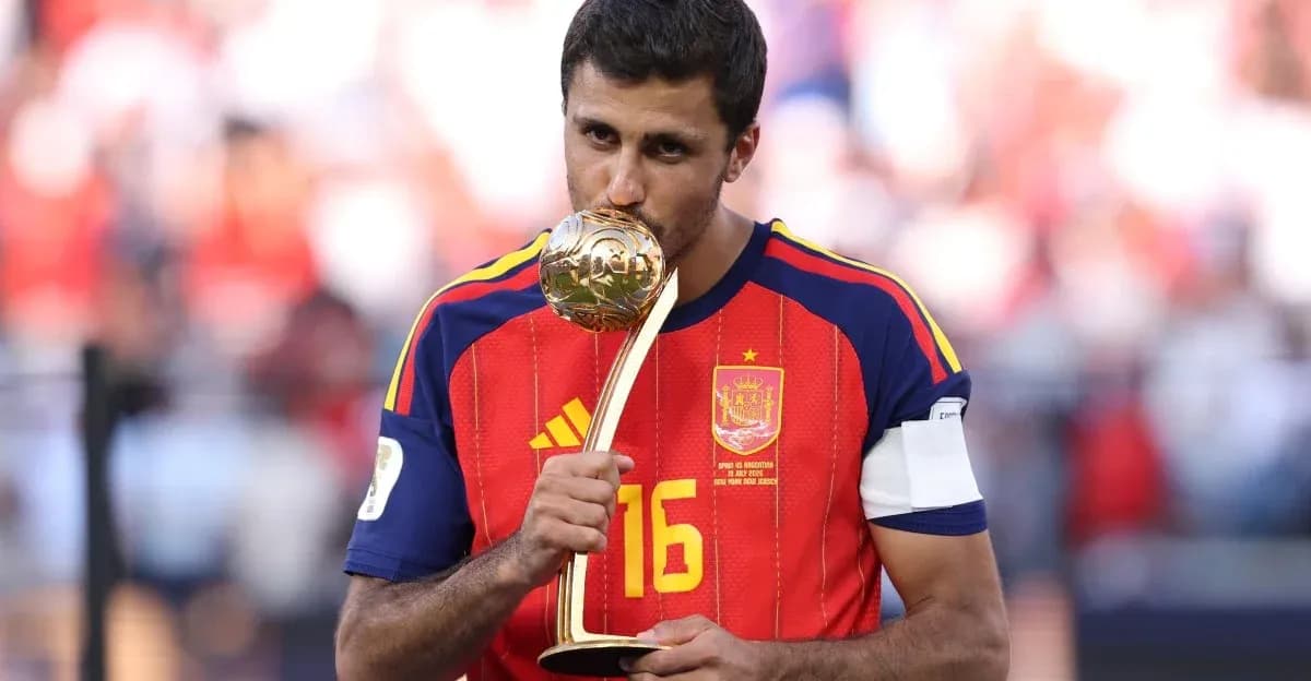 Игрок в форме Испании целует трофей чемпионата