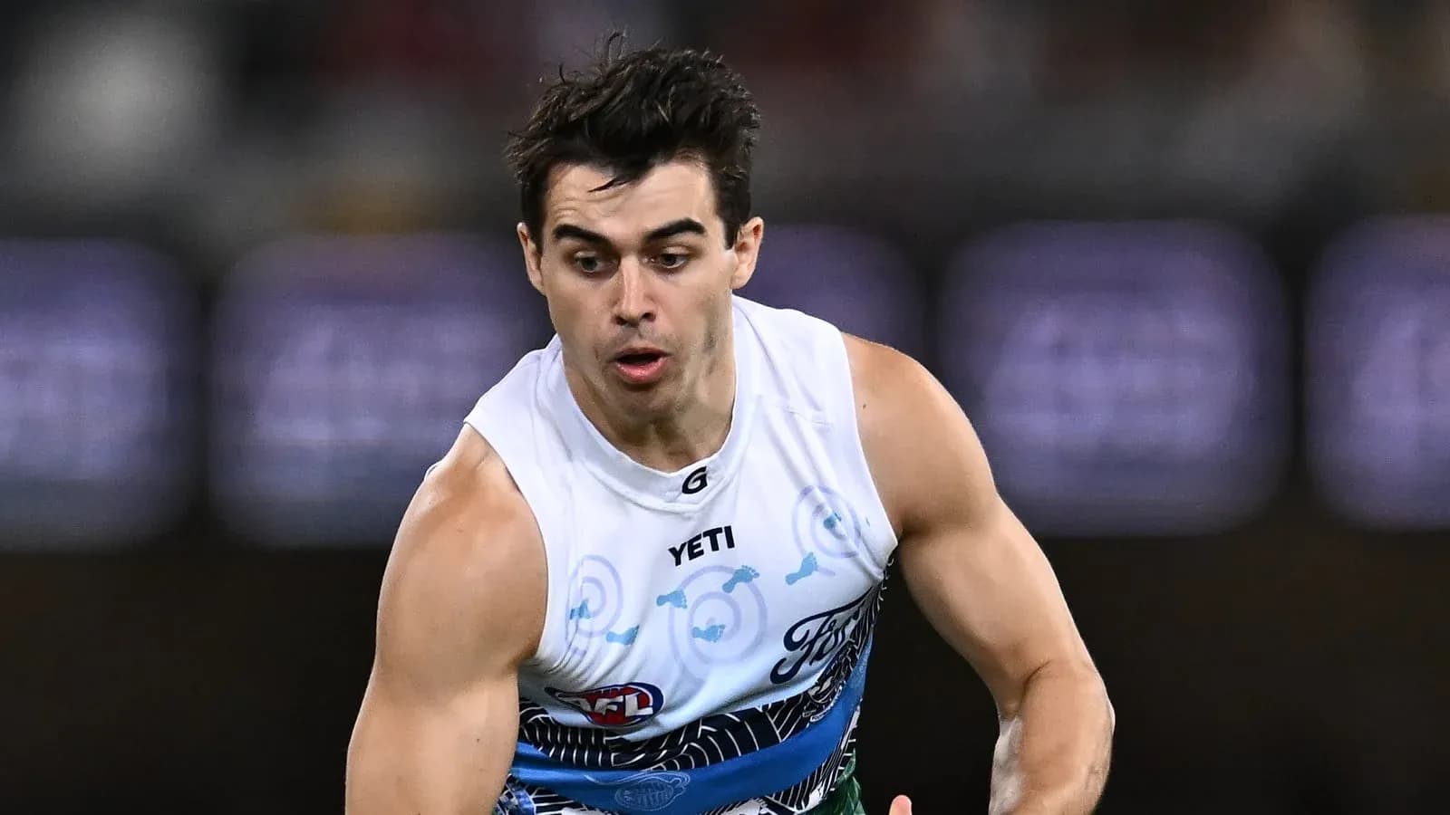 Игрок бежит с мячом на поле AFL Игрок бежит с мячом на поле AFL